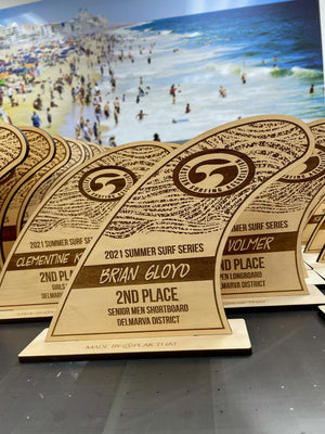 a photo of laser engraved wave-shaped wooden awards for the 2021 Summer Surf Series