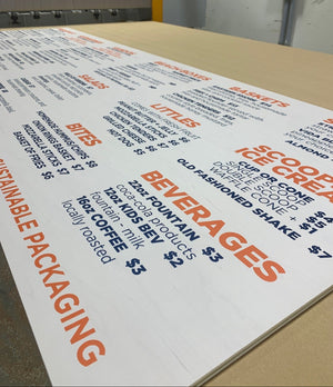 a close-up of a large menu sign with a white background, orange headings and black text