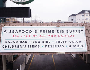 a photo of a large restaurant sign with a white background and black and red text mounted on a roof