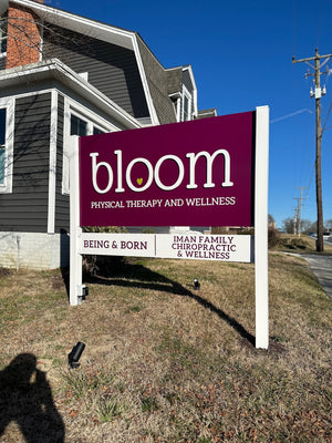 a photo of a purple sign with raised white lettering for Bloom Physical Therapy and Wellness