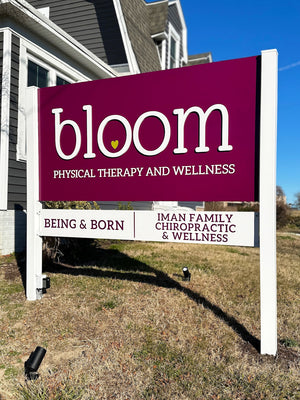 a photo of a purple sign with raised white lettering for Bloom Physical Therapy and Wellness