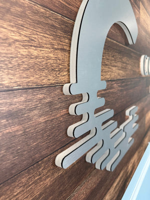 a closeup of a sign for Coastal Life Realty showing the raised aluminum logo mounted to a wooden background