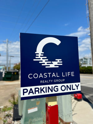 a photo of a small navy blue and white parking sign for Coastal Life Realty