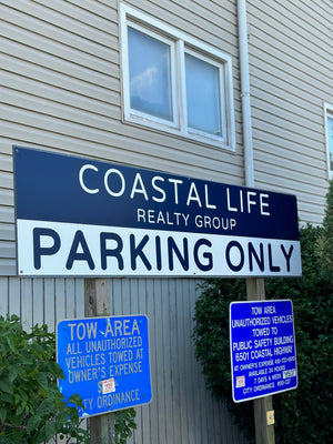 a photo of a navy blue and white parking sign for Coastal Life Realty