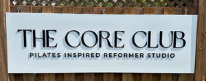 a closeup photo of The Core Club sign with raised black text on a white background