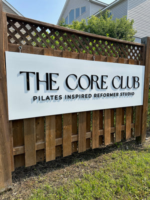 a photo of The Core Club sign with raised black text on a white background