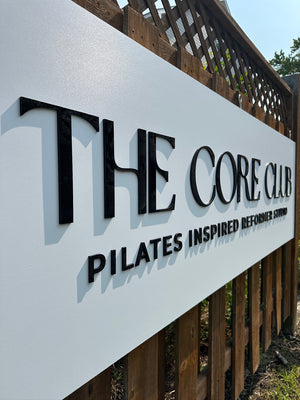 an angled photo of The Core Club sign showing the raised black text