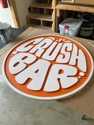 a photo of a circular sign for Crush Bar with an orange background and a white raised border and lettering