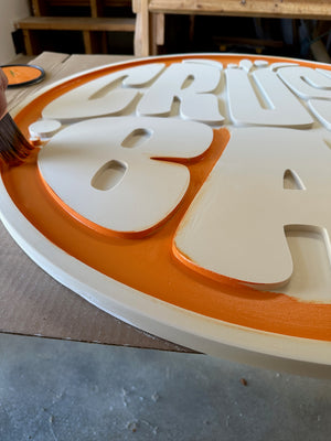 a photo of Justin painting the orange background of a sign for Crush Bar