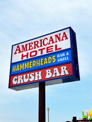 a photo of a lightbox sign with inserts for the Americana Hotel, Hammerheads Bar & Grill, and Crush Bar