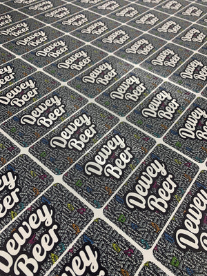 an angled photo of a large sheet of material with many small rectangular "Dewey Beer" prints on it