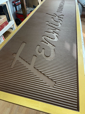 an angled photo of a rectangular brown sign with a golden border, without the white text inserts