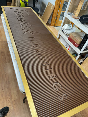 an angled photo of a rectangular brown sign with a golden border, without the white text inserts