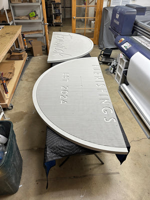 a photo of the two unpainted halves of the circular Fenwick Furnishings sign