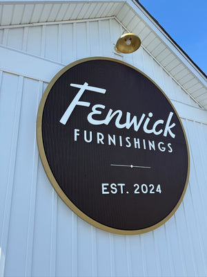 an angled photo of the circular Fenwick Furnishings sign mounted to an exterior wall