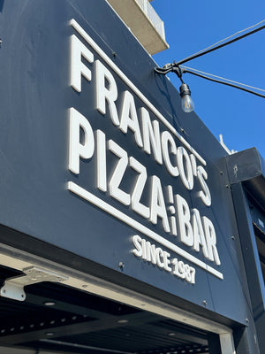 an angled closeup photo of a navy blue sign showing the raised white text