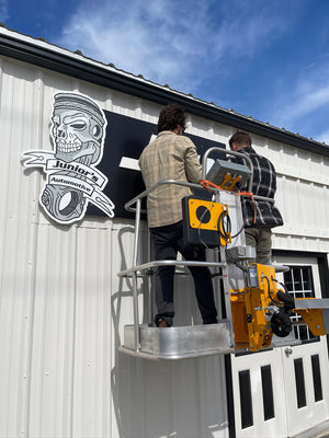 a photo of Wyatt and Justin installing the Junior's Automotive sign above the entrance
