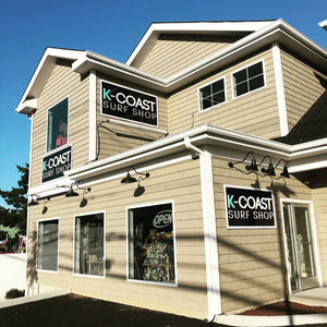 a photo of three K-Coast Surf Shop signs mounted to the exterior of the building