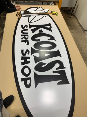 a photo of a large K-Coast Surf Shop logo on wood in the shop