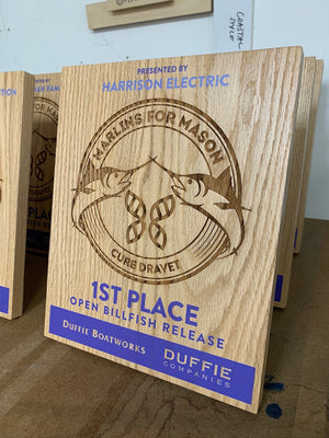 a closeup of a Marlins for Mason 2023 award on laser engraved wood with blue printed lettering