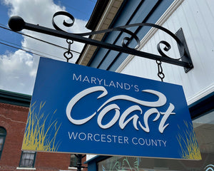a hanging sign with a blue background and raised white text for Maryland's Coast