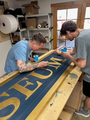 a photo of Justin and Reeves painting half of the Museum of Ocean City sign