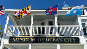 a photo of the Museum of Ocean City sign with four flags flying above it