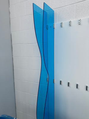 an angled photo of a part of an abstract art piece made of light blue acrylic being mounted to a wall