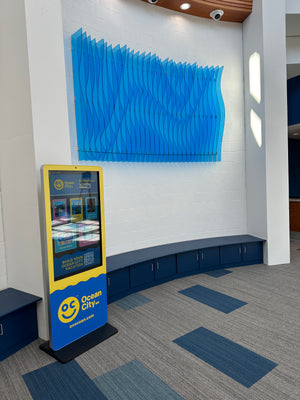 an angled photo of an abstract art piece made of light blue acrylic mounted to a wall