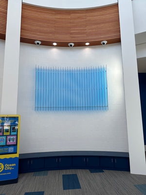 a photo of an abstract art piece made of light blue acrylic mounted to a wall