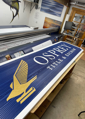 Large sign with 'Osprey Title & Escrow' logo in a workshop setting