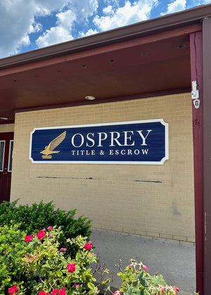 Osprey Title & Escrow sign on a building exterior with flowers and sky in the background