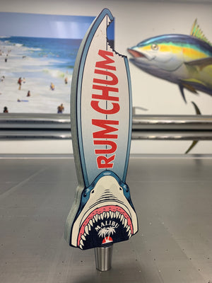 a photo of a surfboard shaped tap handle with a bite missing and a shark head
