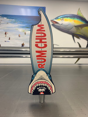 a photo of a surfboard shaped tap handle with a bite missing and a shark head