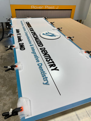a photo of the Centers for Specialized Dentistry sign with clamps holding it together while the adhesives set