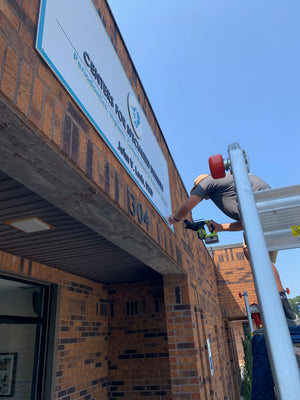 a photo of Wyatt mounting the final Centers for Specialized Dentistry sign above the entrance