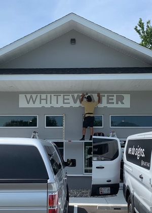 a photo of Wyatt mounting the lettering for Whitewater Crossfit above the entrance