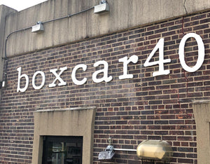 a photo of aluminum lettering saying "boxcar40" mounted to a brick wall